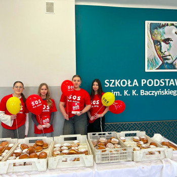 Zdjęcie czworki dziewczyn. Na stole kartony z pązckami. W tle logotym szkoły z opisem