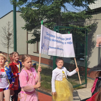 Dzieci idące w pochodzie, Dziewczynki trzymają baner zacęcający do czytania