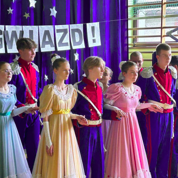 Uczniowie ubrani w stroje stylizowane na historyczne, stojący w rzędzie na scenie podczas gali laureatów